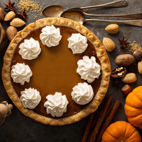 Sweet pumpkin pie decorated with whipped cream overhead shot with copy space