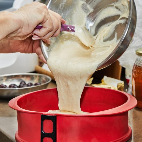 Cook puts the dough into a silicone cake pan.