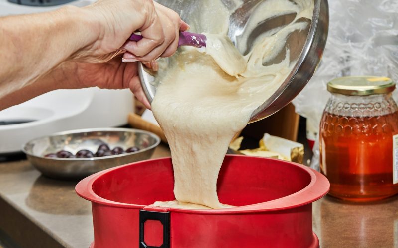 Cook puts the dough into a silicone cake pan.