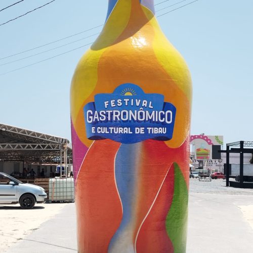 Escultura gigante de garrafa com areia colorida marca entrada do 5º Festival Gastronômico e Cultural de Tibau