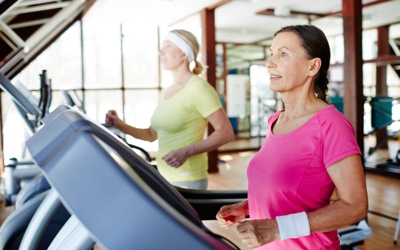 Two active and helathy sportswomen exercising on treadmills in modern fitness center
